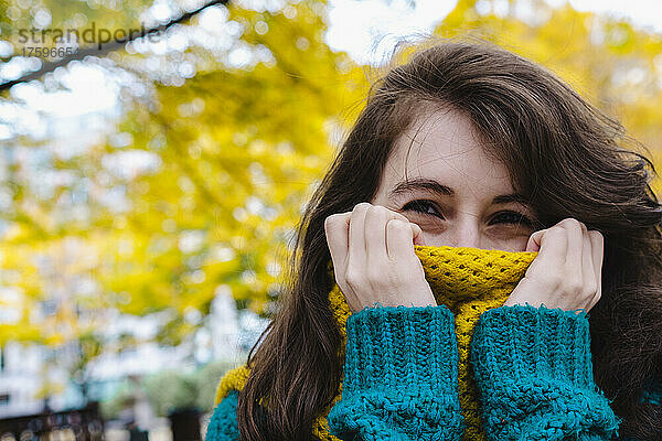 Frau bedeckt Mund mit Schal im Park