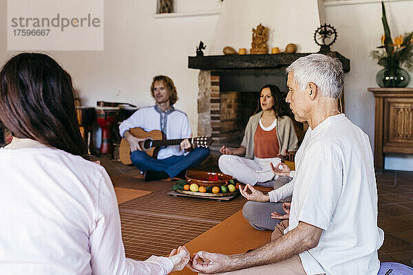 Gemischtrassige Freunde meditieren bei Musiktherapie