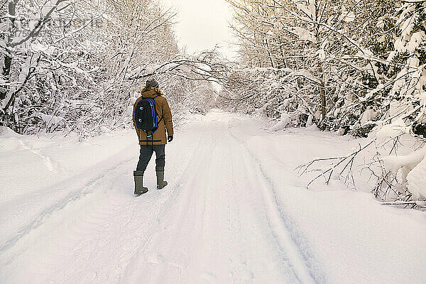Männlicher Wanderer  der im schneebedeckten Wald spaziert