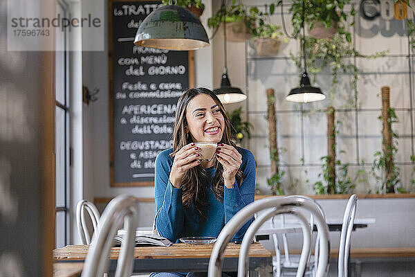 Glückliche Frau beim Kaffee im beleuchteten Café