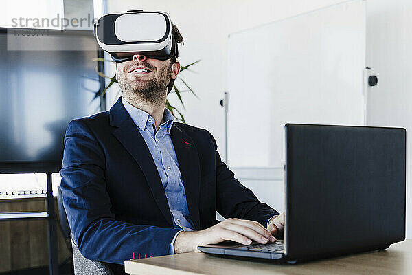 Geschäftsmann mit Laptop und Virtual-Reality-Headset im Büro