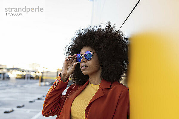 Frau mit Sonnenbrille an der Wand