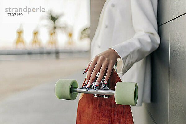 Frau mit Skateboard an der Wand