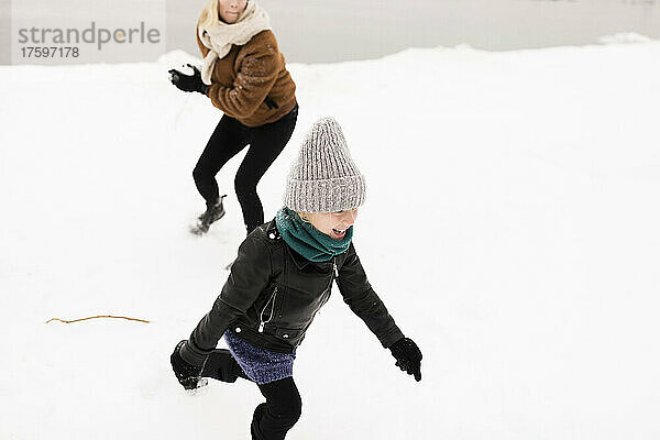 Glückliche Mutter und Tochter  die im Winter mit Schnee spielen