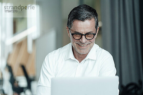 Lächelnder Geschäftsmann mit Brille  der im Büro arbeitet