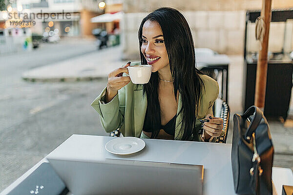 Nachdenkliche Geschäftsfrau trinkt Kaffee im Straßencafé