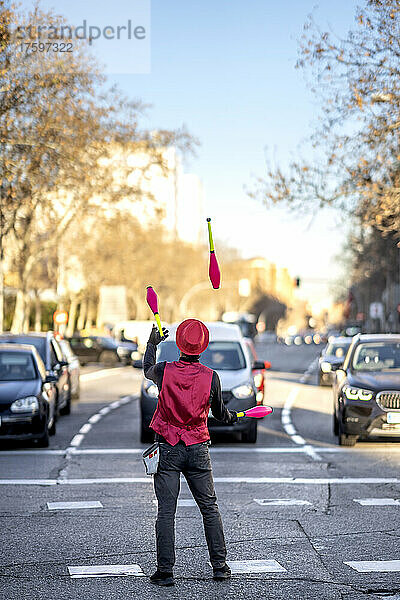 Solokünstler jongliert mit Pins vor Autos auf der Straße