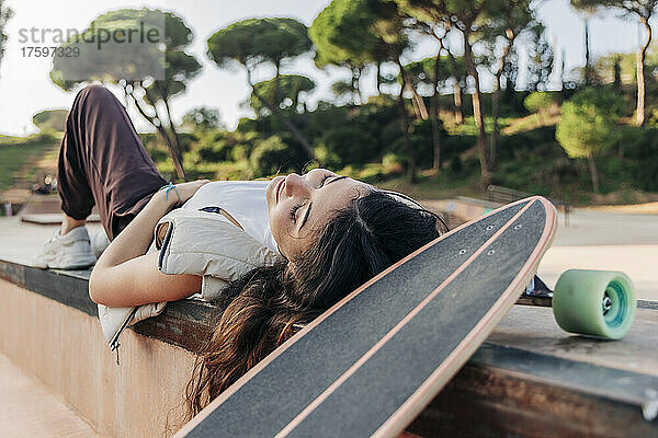 Frau liegt mit Skateboard im Park