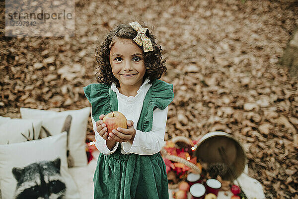 Lächelndes Mädchen hält Apfel im Wald zu Weihnachten