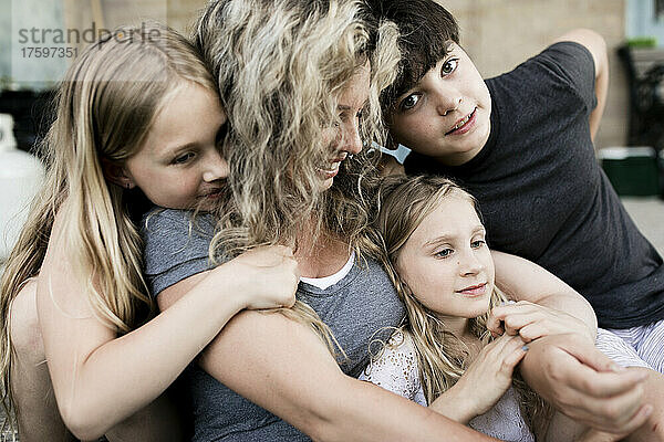 Lächelnde Mutter sitzt mit Sohn und Töchtern