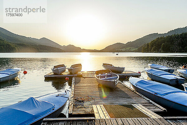 Boote liegen bei Sonnenuntergang am Steg am Ufer des Fuschlsees