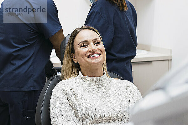 Lächelnde Frau sitzt auf dem Zahnarztstuhl in der Klinik