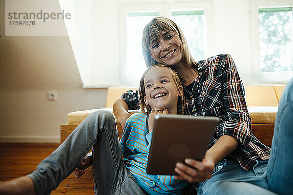 Mutter und Sohn mit Tablet-PC lachen zu Hause