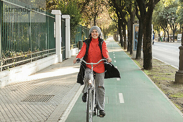 Lächelnde junge Frau  die auf dem Fahrradweg radelt