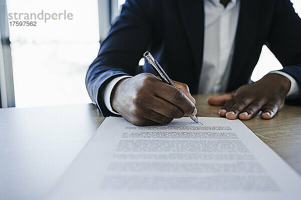 Kunde unterzeichnet Vertrag am Tisch im Büro