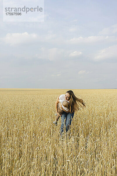 Junge Mutter spielt mit Sohn im Weizenfeld