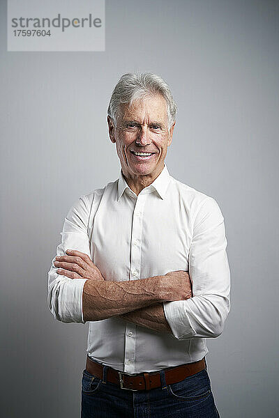 Confident elderly businessman with arms crossed in studio