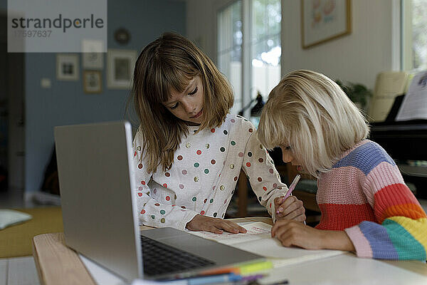 Mädchen hilft Schwester bei Hausaufgaben zu Hause