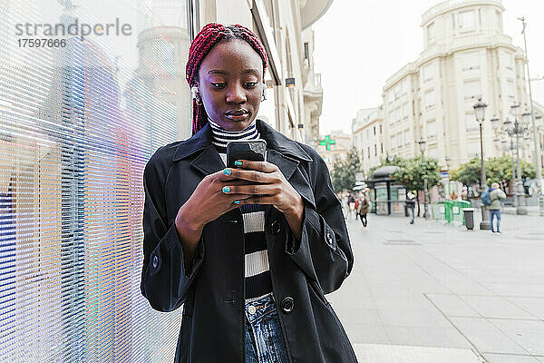 Junge Frau benutzt Mobiltelefon in der Stadt