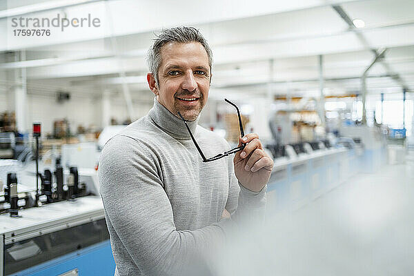 Lächelnder Geschäftsmann mit Brille in der Industrie