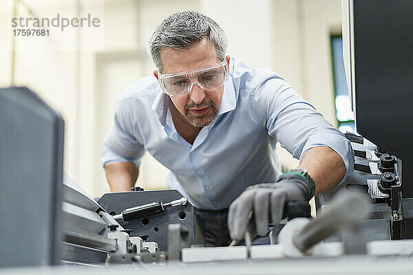 Geschäftsmann mit Schutzbrille untersucht Maschinen in der Fabrik