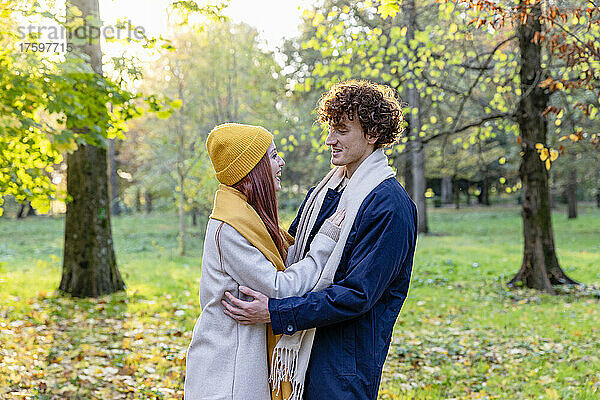 Lächelndes Paar redet und umarmt sich im Herbstpark