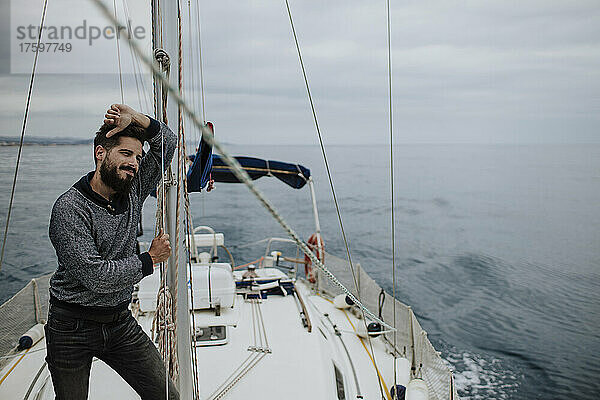Nachdenklicher Mann lehnt am Mast eines Segelboots im Mittelmeer