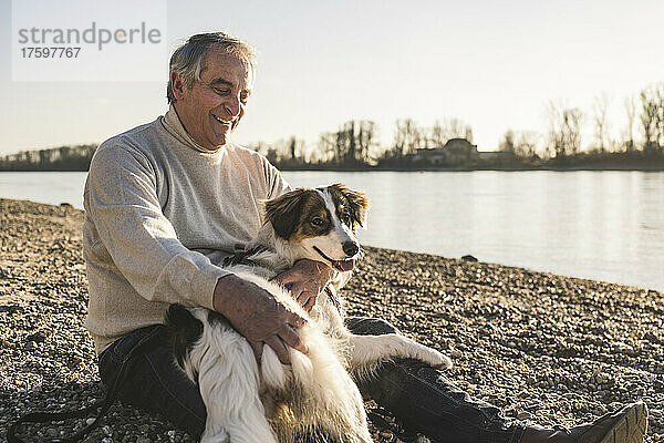 Glücklicher älterer Mann  der an einem sonnigen Tag seinen Hund anschaut