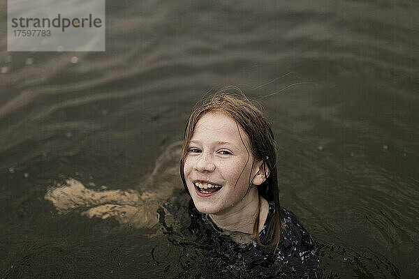 Glückliches Mädchen mit braunen Haaren  das im Wasser spielt