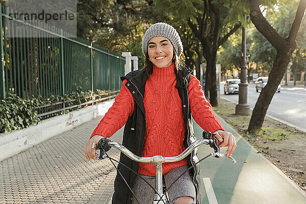 Lächelnde schöne Frau mit Fahrrad unterwegs