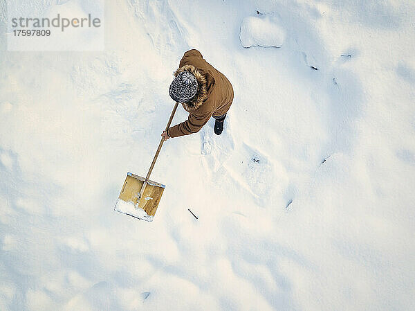 Man cleaning snow with snow shovel in winter