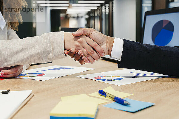 Geschäftskollegen geben sich im Coworking-Büro die Hand
