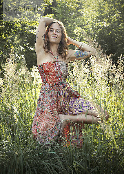 Frau steht auf einem Bein inmitten von Pflanzen im Wald