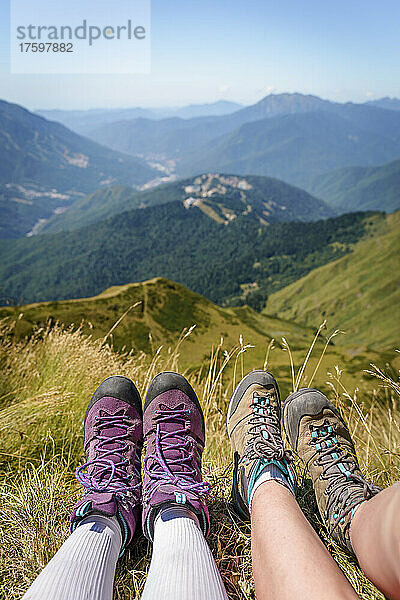 Friends wearing hiking boots relaxing on grass at mountain in Caucasus Nature Reserve  Sochi  Russia