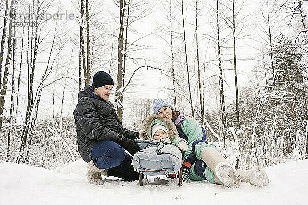 Vater und Mutter mit Tochter genießen den Schnee im Winterwald