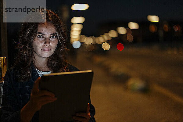 Schöne Frau mit Tablet-PC auf der Stadtstraße in der Nacht