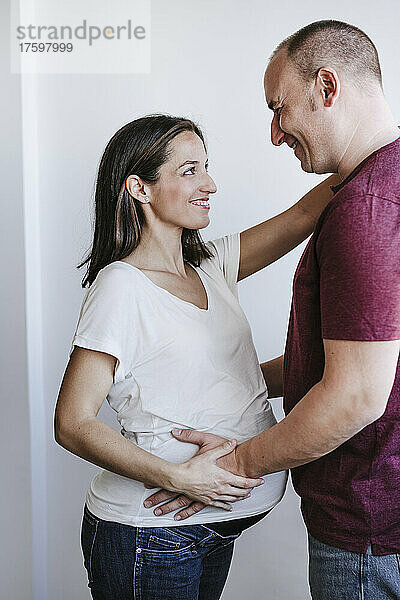 Glücklicher Mann schaut schwangere Frau zu Hause an