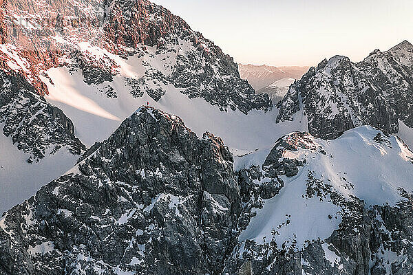 Abenteuerlustiger Mann steht bei Sonnenuntergang auf einem schneebedeckten Berg  Vorderer Tajakopf  Ehrwald  Tirol  Österreich