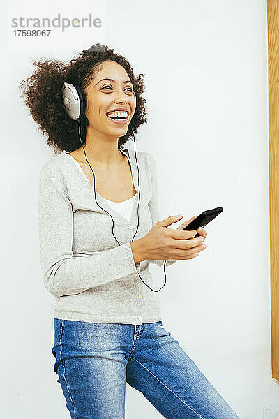 Happy woman listening music through headphones