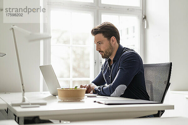 Geschäftsmann arbeitet am Laptop am Schreibtisch im Büro