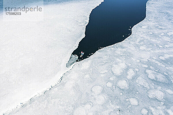 Deutschland  Bayern  Luftaufnahme eines einsamen Mannes beim Paddeln zwischen Eisschollen im Eibsee