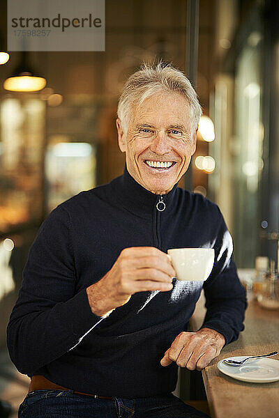 Smiling senior man having coffee in cafe