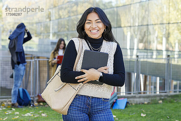 Fröhliche Frau mit Tablet-PC auf dem Universitätscampus