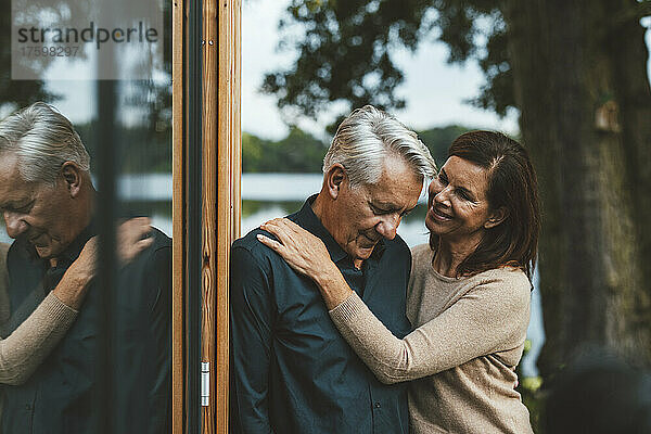 Lächelnde Frau schaut älteren Mann an  der an einer Glaswand steht