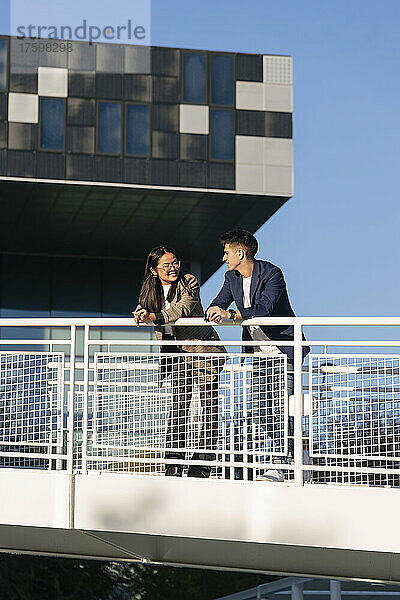 Business colleagues talking to each other leaning on railing