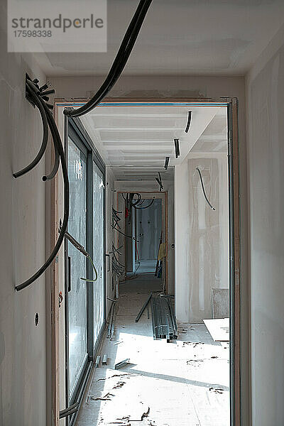 Leerer Korridor mit Kabeldrähten  die durch die Tür auf der Baustelle gesehen werden