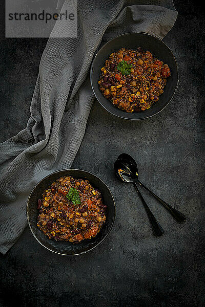 Studio shot of two bowls of vegan quinoa stew with vegetables and chick-peas