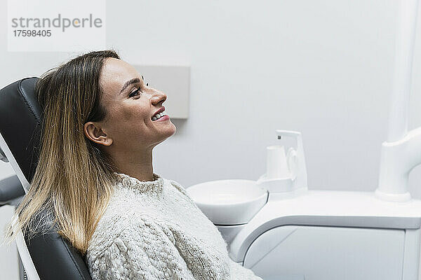 Glückliche Frau auf Zahnarztstuhl im Operationssaal der Klinik
