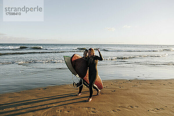 Fröhliche Surferinnen mit Surfbrettern  die am Strand von Gran Canaria  Kanarische Inseln  auf dem Sand spazieren