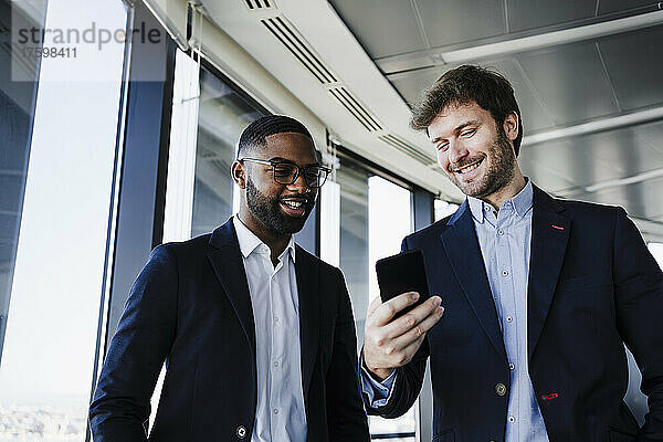 Glückliche Geschäftsleute teilen ihr Smartphone im Coworking-Büro